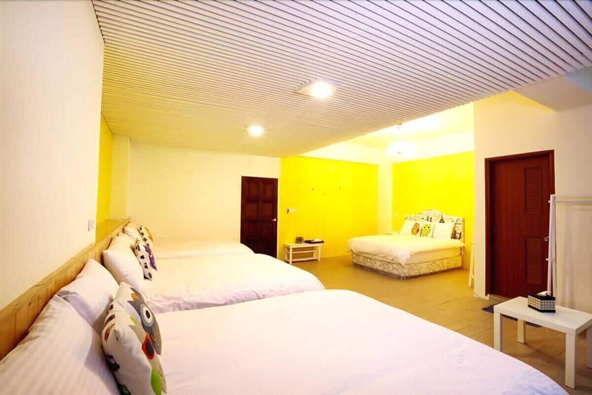A hotel room with two beds, a small table, and a door.