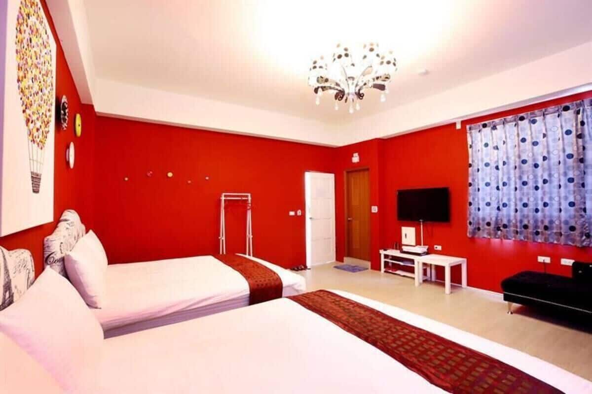 A room with two beds, a TV, a desk, and a chandelier.