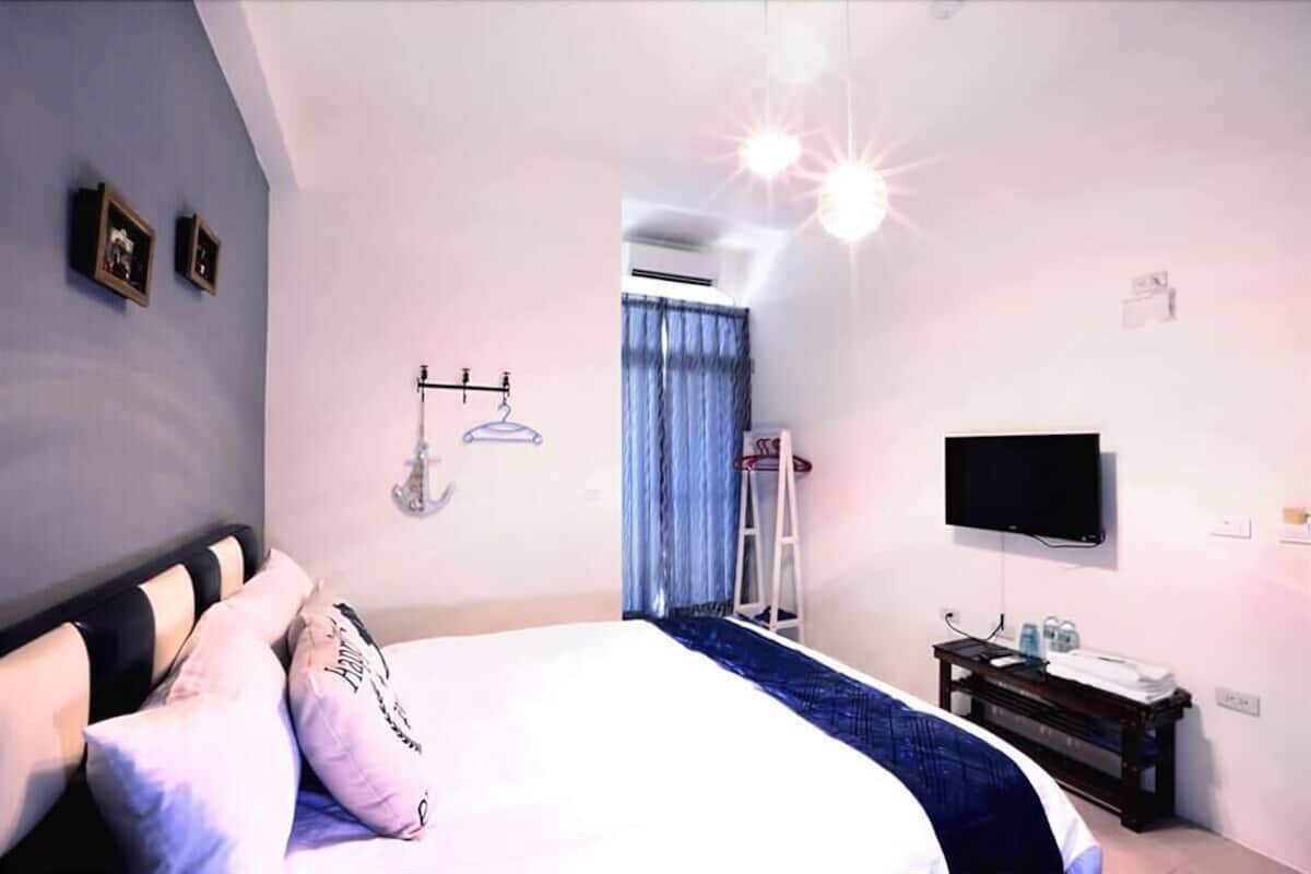 A bedroom with a bed, a TV, a wardrobe, and a window with curtains.