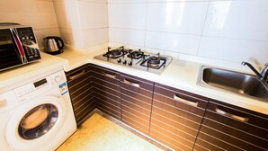 A compact kitchen with a washing machine, microwave, gas stove, and a sink.