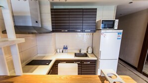 A compact kitchen with a microwave, sink, and a small refrigerator.
