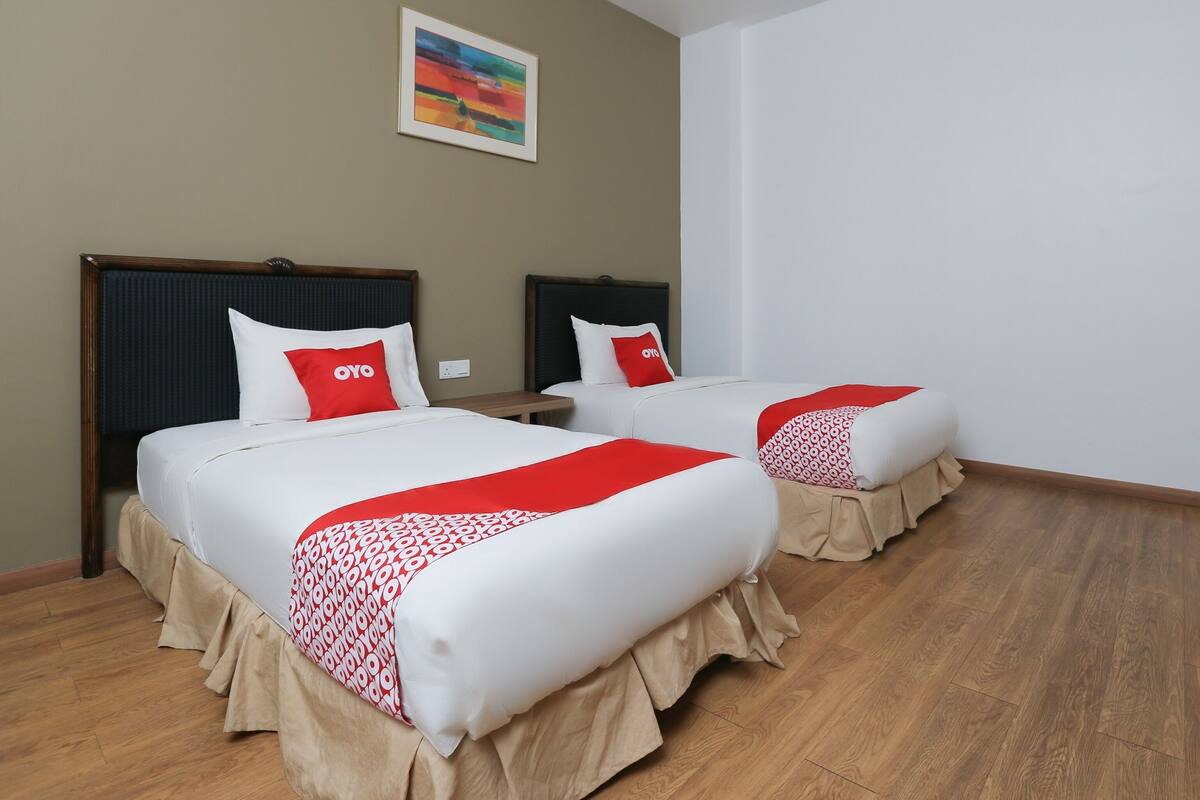 A hotel room with two beds, each with a red and white bedspread and matching pillows.
