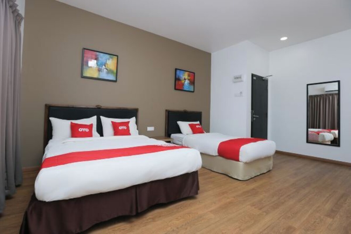 Une chambre d’hôtel avec deux lits, une porte et un miroir.