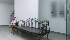 A black metal bench with a cushion, positioned in a room with white walls and a tiled floor. - OYO 89915 East Mount Hotel (Kukup)