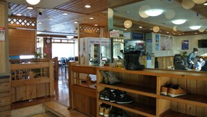 Un interior de restaurante con mobiliario de madera, una exhibición de zapatos y una barra con dispensador de bebidas.
