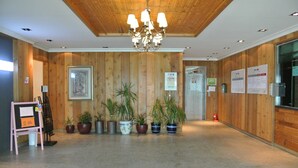 Un vestíbulo amplio con paneles de madera, un candelabro y varias plantas en macetas.