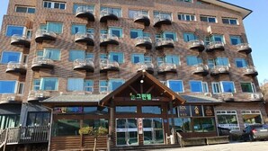 Un hotel de varios pisos con balcones, entrada de madera y señalización para una escuela.