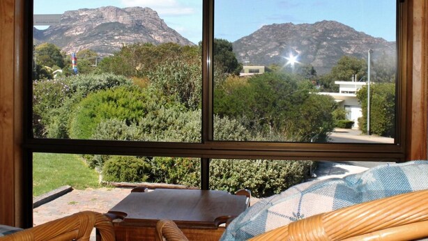 Habitació amb una finestra gran que ofereix vista a una muntanya i un edifici modern.