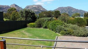 Vista d'un pati amb una zona enjardinada, una tanca de fusta i una barana metàl·lica.
