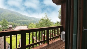 A wooden balcony with a view of a green landscape and mountains. - Chalet Resort (Pyeongchang)