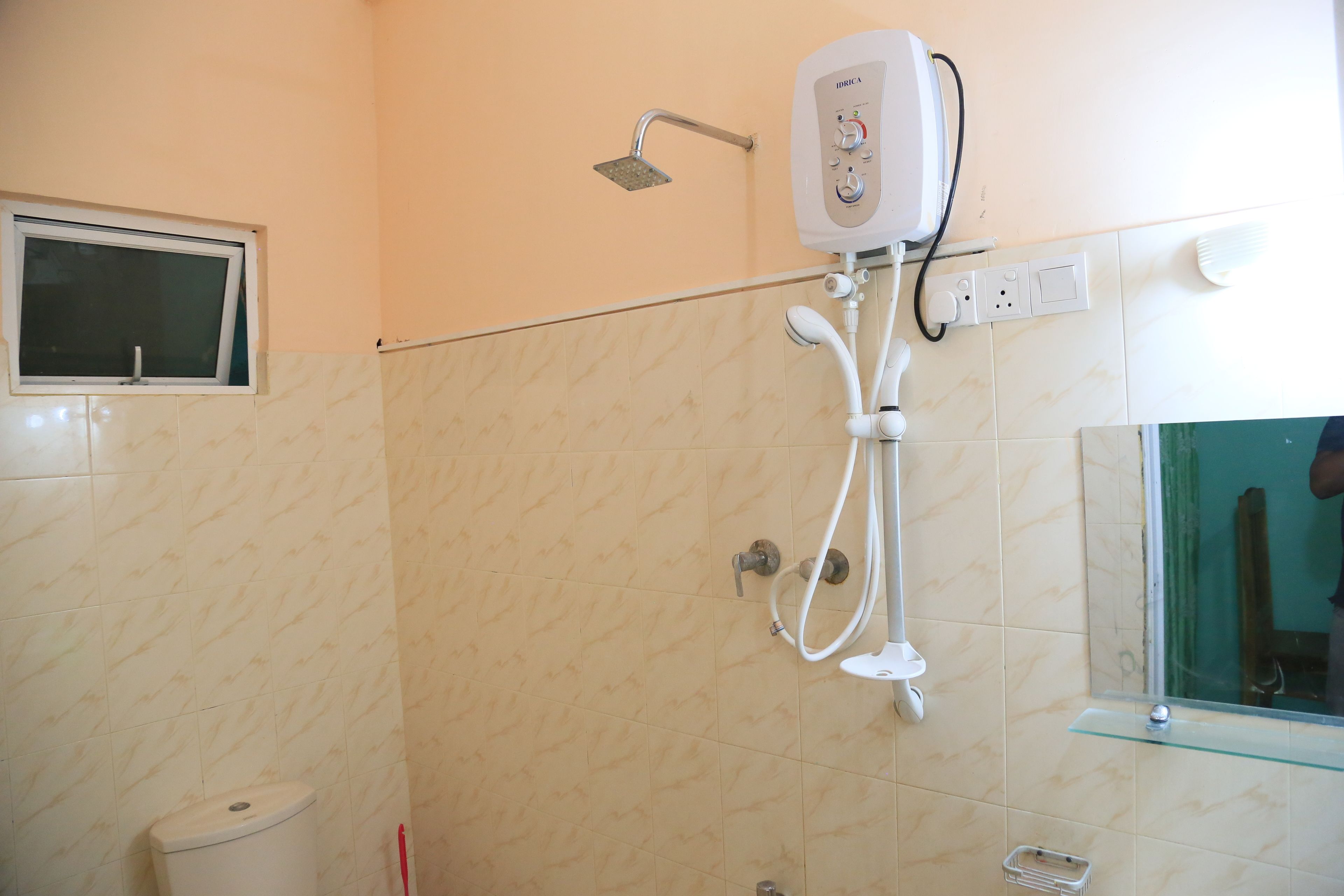 Een badkamer met een douche, toilet en een spiegel.