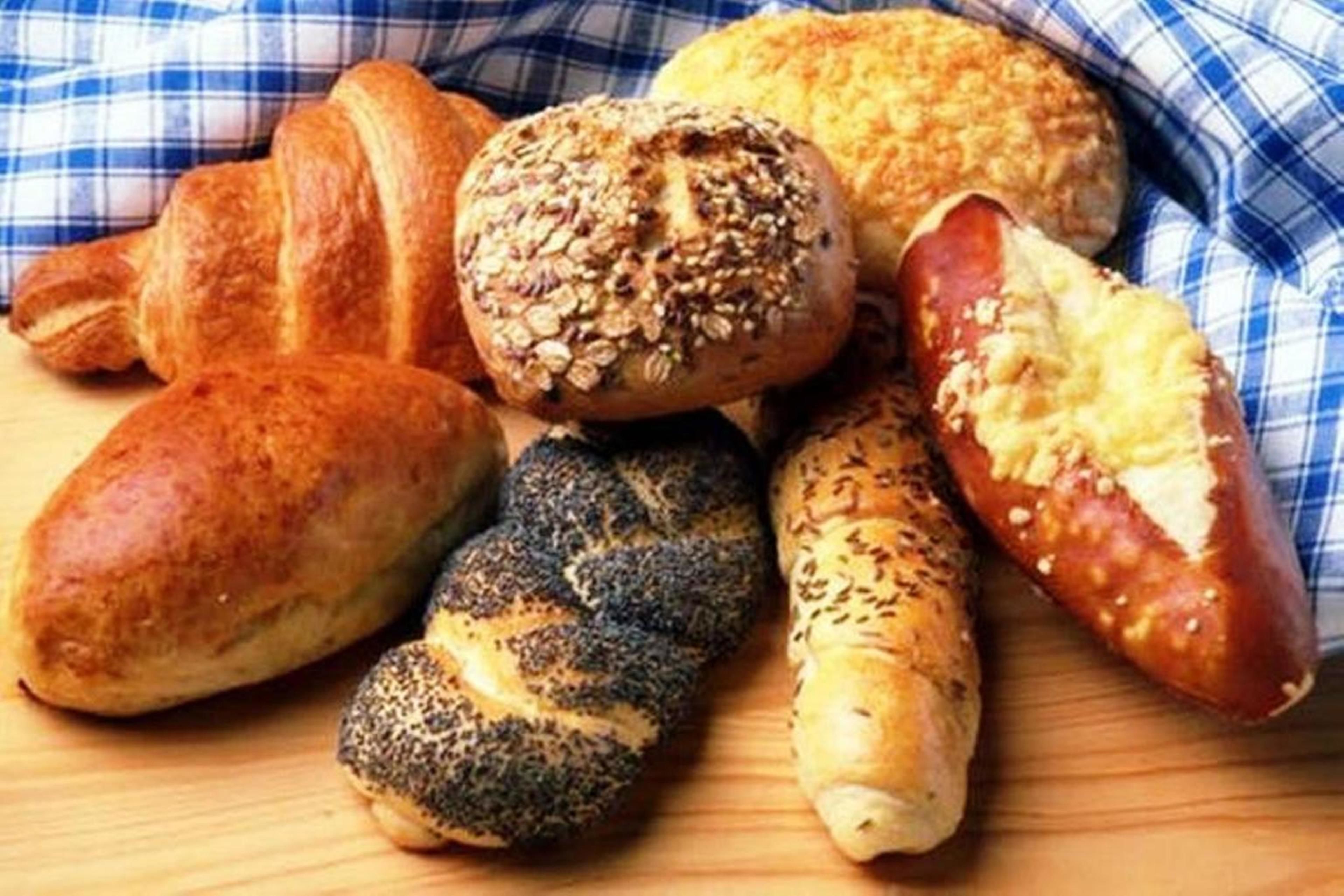 Variedad de productos horneados, incluyendo un croissant, un pan con semillas de sésamo, un pan con semillas de amapola y una baguette.