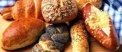 Variedad de productos horneados, incluyendo un croissant, un pan con semillas de sésamo, un pan con semillas de amapola y una baguette.