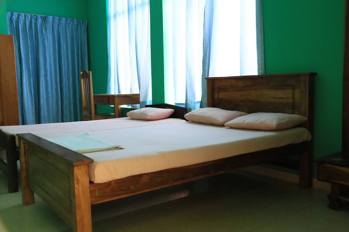 A single bed with a wooden frame and a white mattress, accompanied by two pillows.