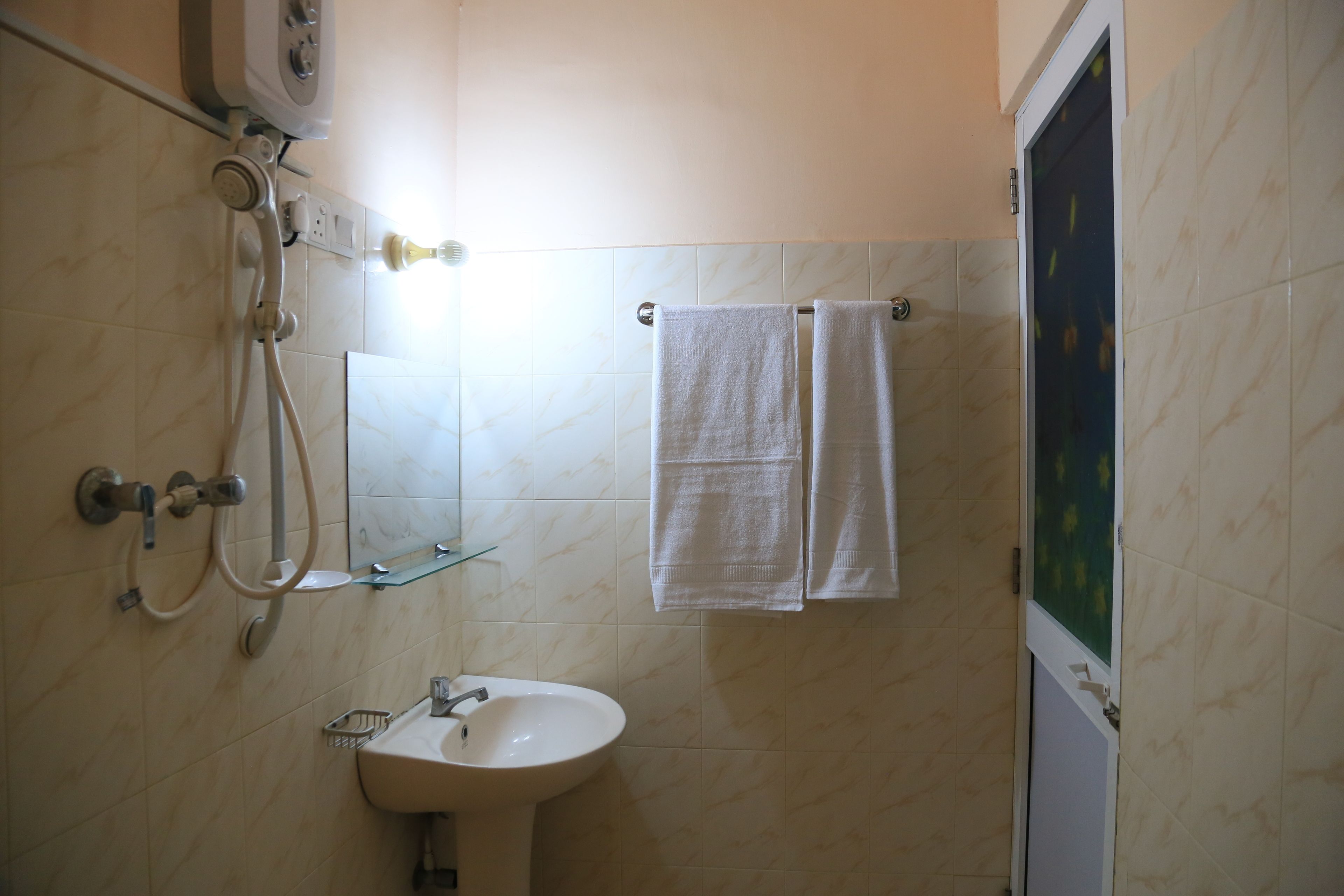 A bathroom with a sink, mirror, two towels, and a shower.