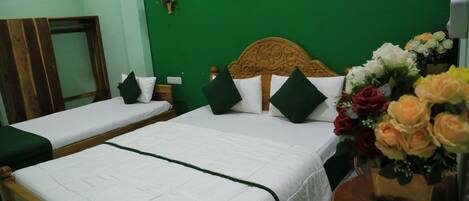 A hotel room with two single beds, green walls, and a wooden headboard.