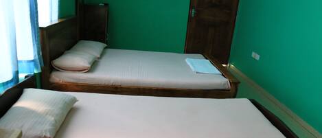 Una habitación con dos camas individuales, cabeceros de madera y paredes verdes.