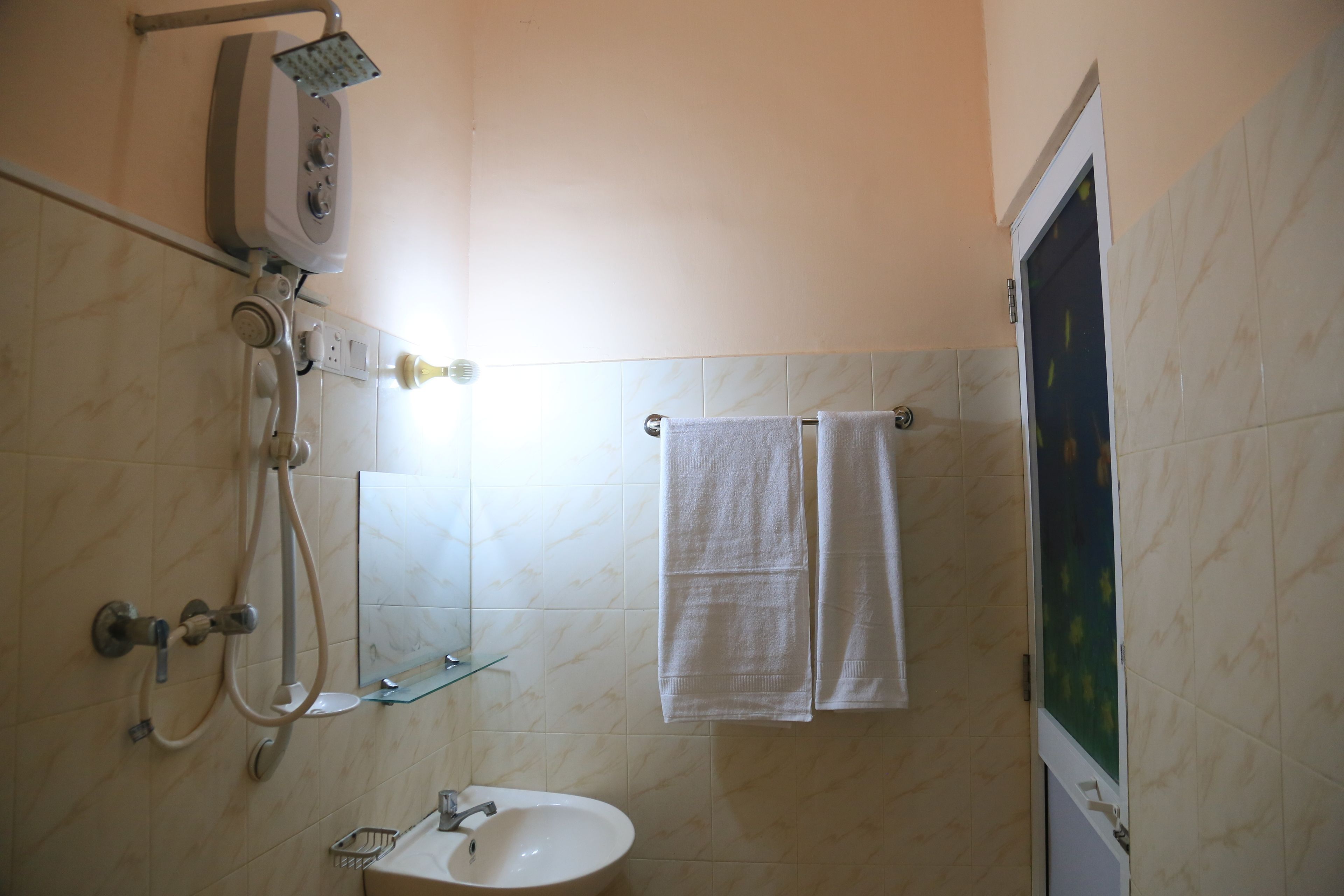 A bathroom with a shower, sink, and two towels hanging on a rack.