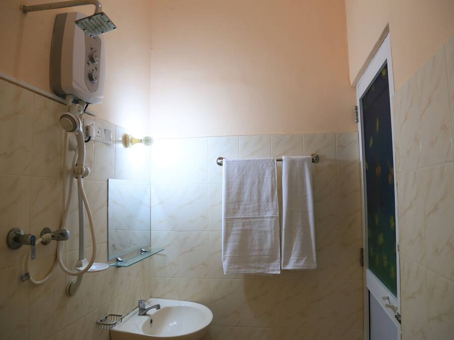 A bathroom with a shower, sink, and two towels hanging on a rack.