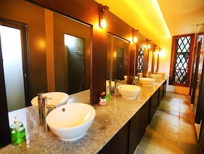 A hotel bathroom with multiple sinks, a mirror, and a shower stall. - Little Hpa An Hostel (Hpa-An)
