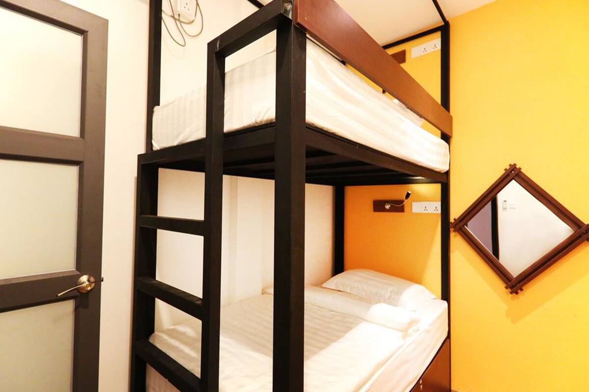 Habitación con literas, puerta y espejo en la pared.