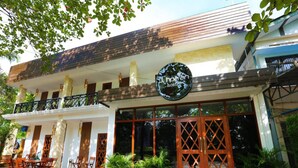 Une auberge de jeunesse avec une enseigne indiquant « Hapa Hostel » et un balcon équipé de sièges.