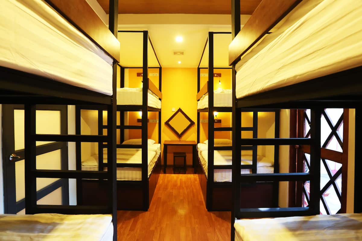 Una habitación con literas, suelo de madera y una mesa central.