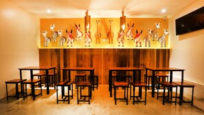 Une pièce avec des tables et des chaises en bois, un mur décoré de motifs zébrés et de girafes, et un téléviseur fixé au mur.