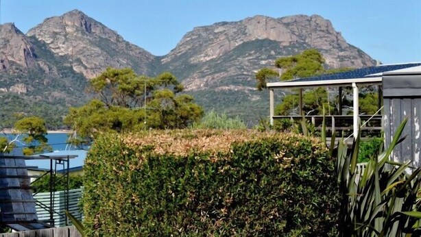 A mountainous landscape with a view of a building that has a covered outdoor area and a solar panel. - Freycinet Sands (Coles Bay)