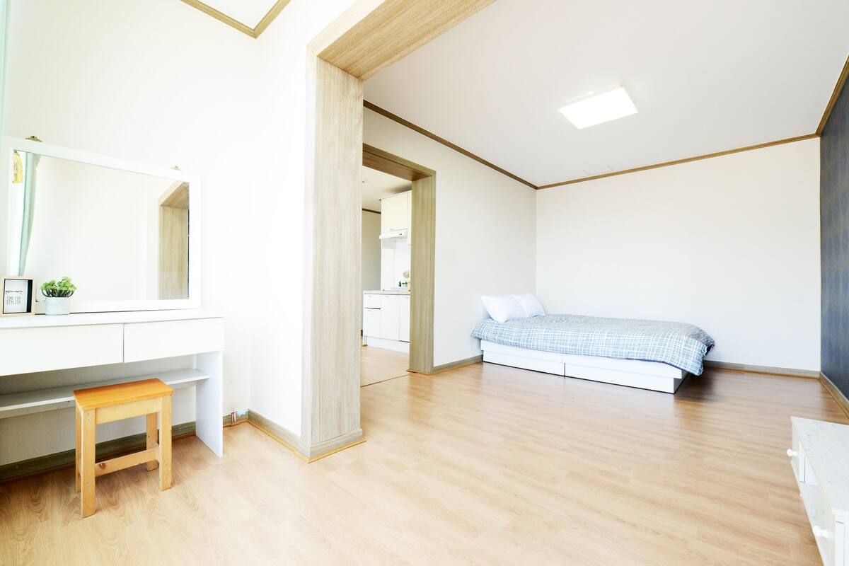 A bedroom with a bed, a desk, and a chair.