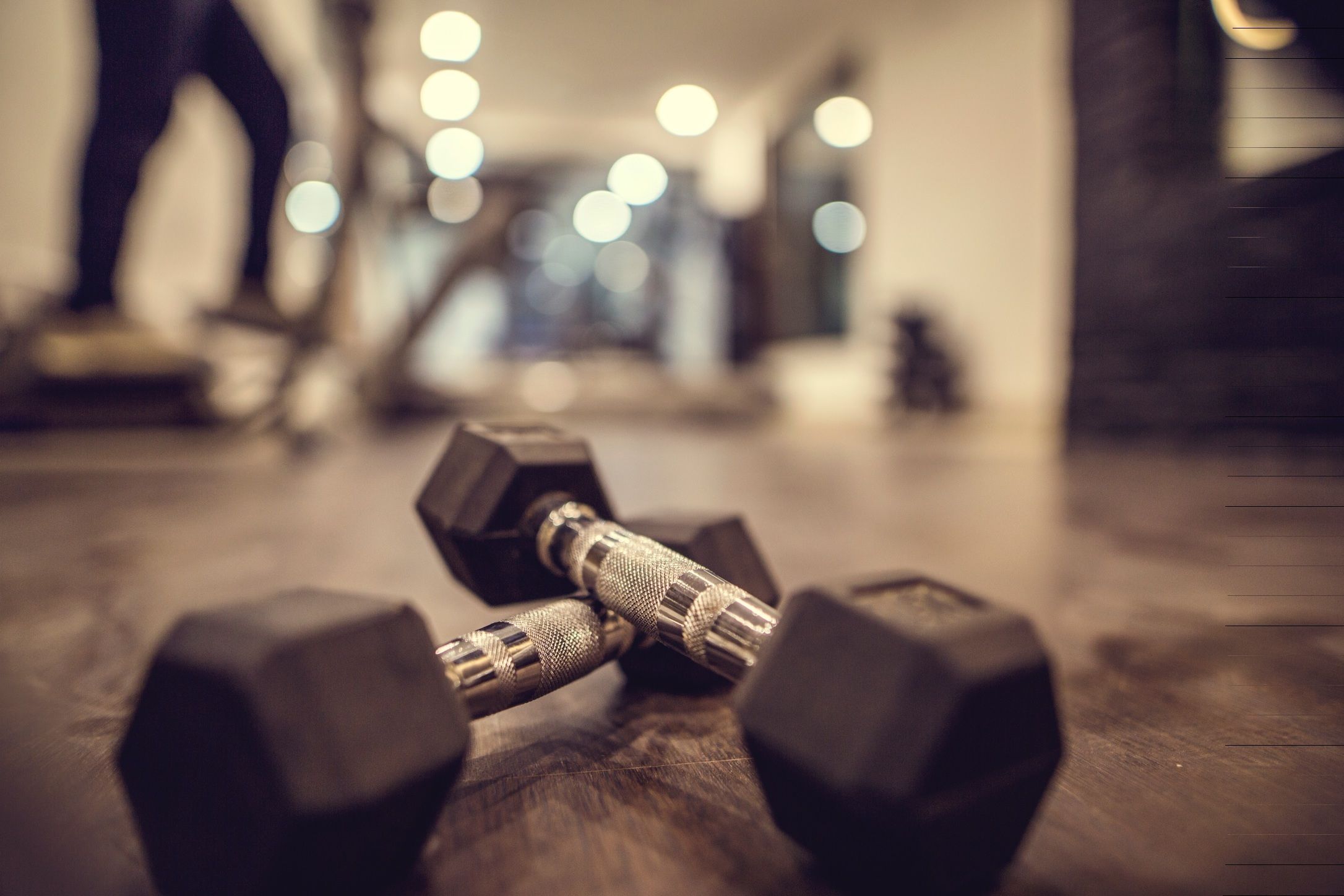 A close-up of two hexagonal dumbbells on a wooden floor.