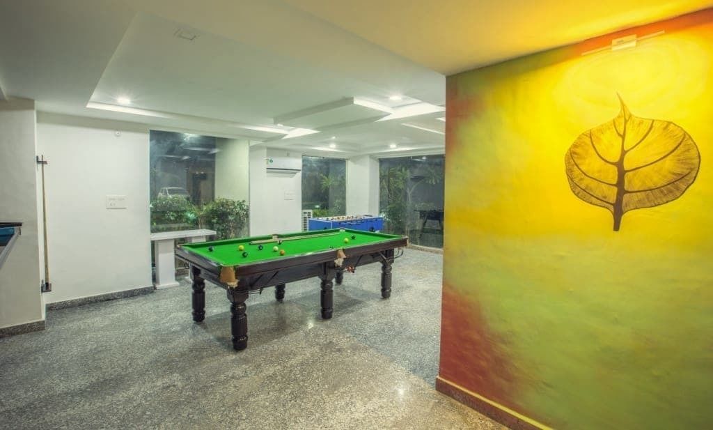 Una mesa de billar en una habitación con un ventanal grande y una pared decorada con un diseño de hojas.