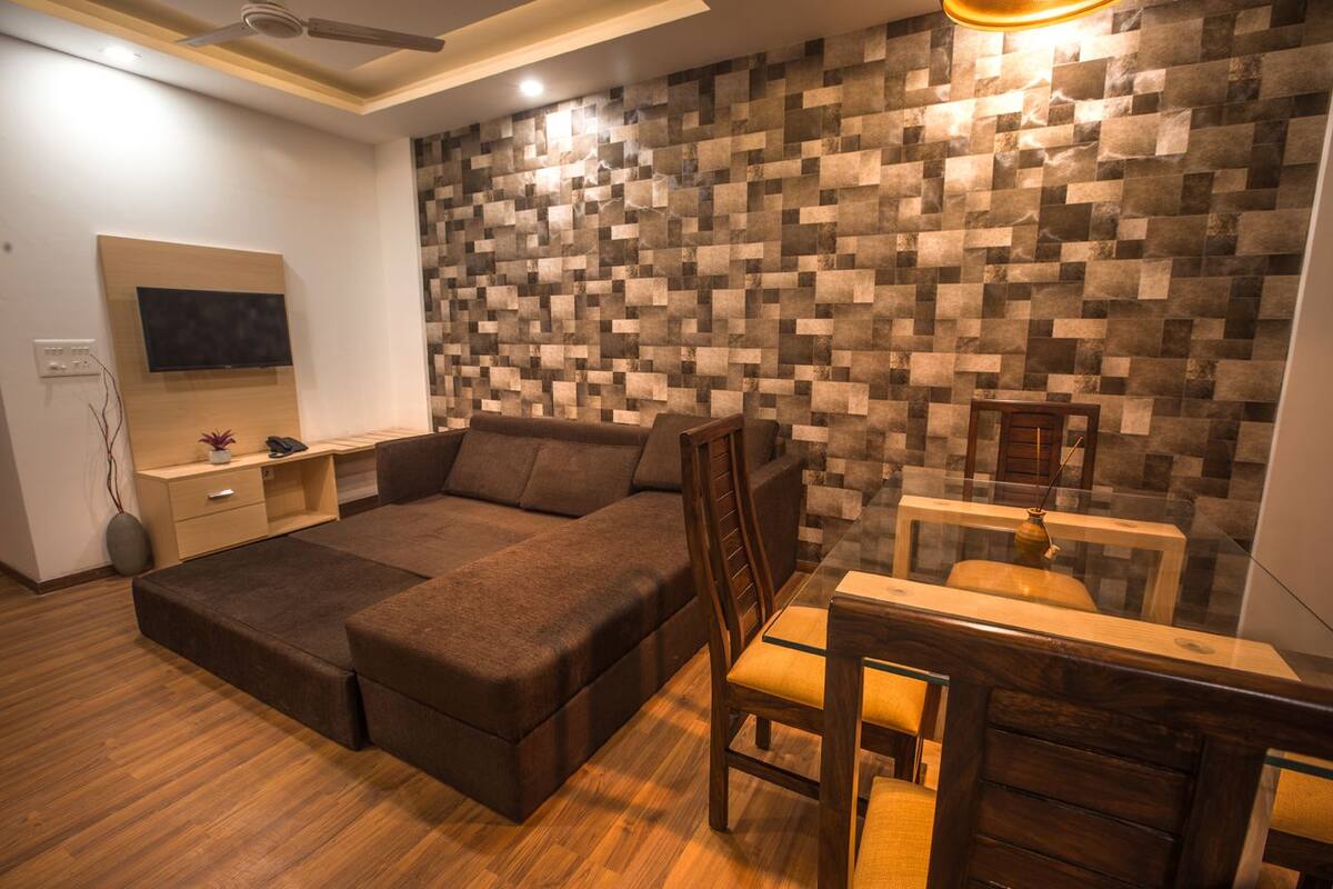 Un dormitorio moderno con sofá cama, un escritorio de madera y una televisión montada en la pared.