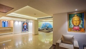 Un vestíbulo amplio con una recepción, un mural de una deidad y una pintura de Buda.