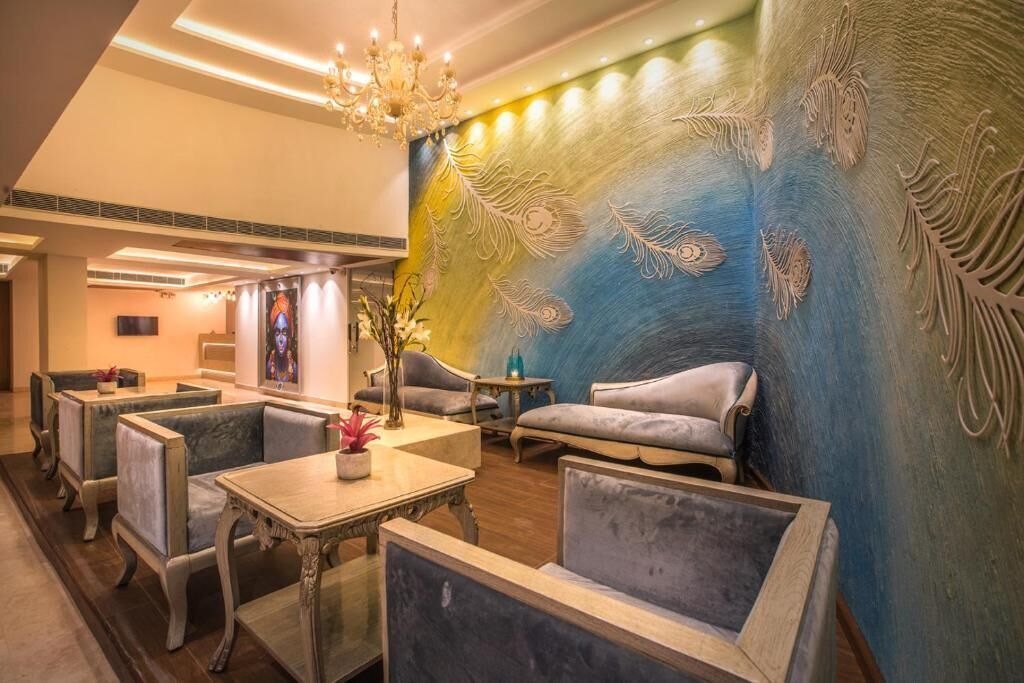 A hotel lobby with seating areas, a chandelier, and a wall with feather patterns.