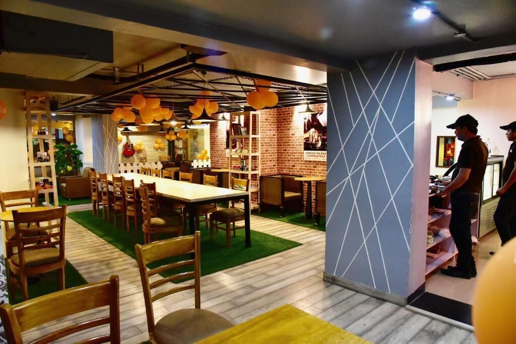 A restaurant with a long communal table, individual seating, and a brick wall.