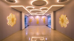 Un pasillo espacioso con diseño moderno en el techo, arte en la pared iluminado y piso pulido.