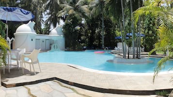 Relax by the serene pool surrounded by lush tropical vegetation and a small water fountain.
