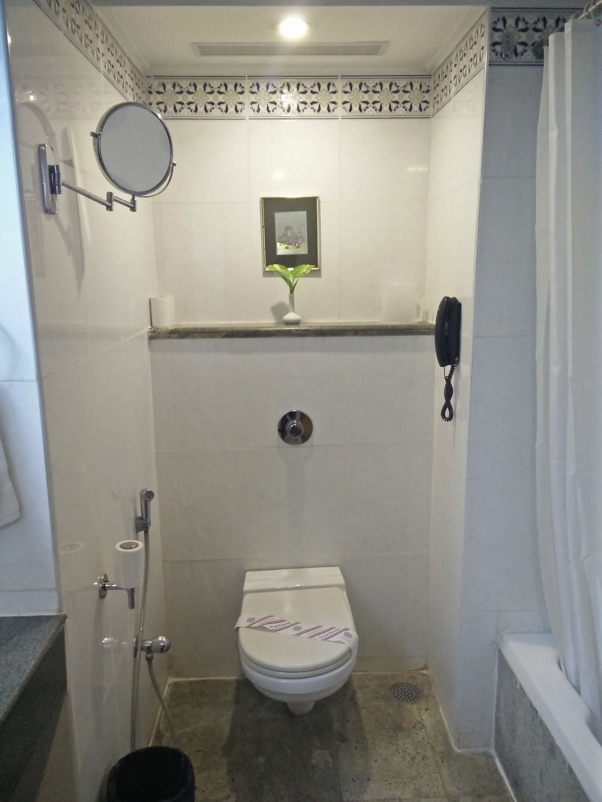 A small, enclosed bathroom with a toilet, a shower, and a sink.
