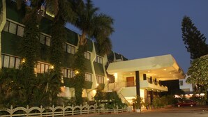 A hotel with a modern design, featuring a prominent staircase, multiple balconies, and lush greenery. - Hotel Parisutham (Thanjavur)