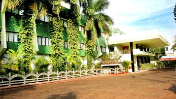 Um edifício com fachada verde, grandes janelas e entrada branca com varanda.