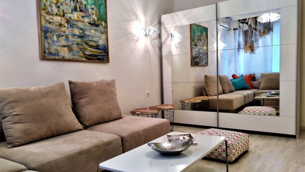 A modern living room with a sofa, a coffee table, and a mirrored wardrobe. - Baratero City I Apartment (Sofia)