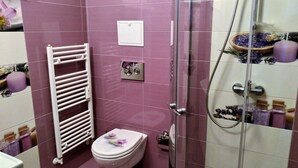 A bathroom with a toilet, a shower, and a towel rack. - Baratero City I Apartment (Sofia)