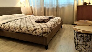 A hotel room with a bed, a bedside table with a lamp, and a round side table with a tray. - Baratero City I Apartment (Sofia)