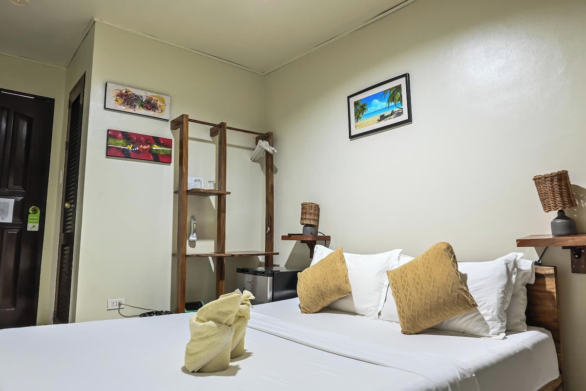 Habitación de hotel con cama, escalera de madera, estante con lámpara y dos cuadros en la pared.