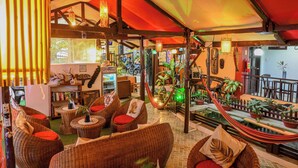 A cozy lounge area with wicker furniture, a hammock, and a small pool.