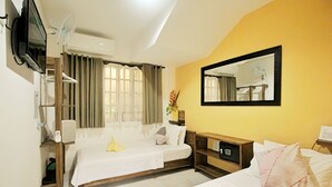 A hotel room with a bed, a bedside table, a mirror, a TV, and a window with curtains.