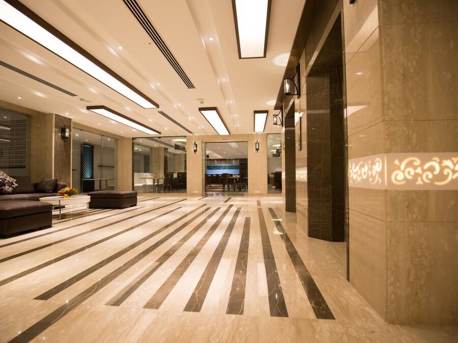 Een ruime lobby met een modern design, met een groot zitgedeelte met banken en een salontafel, een patroon vloer en een receptiebalie.