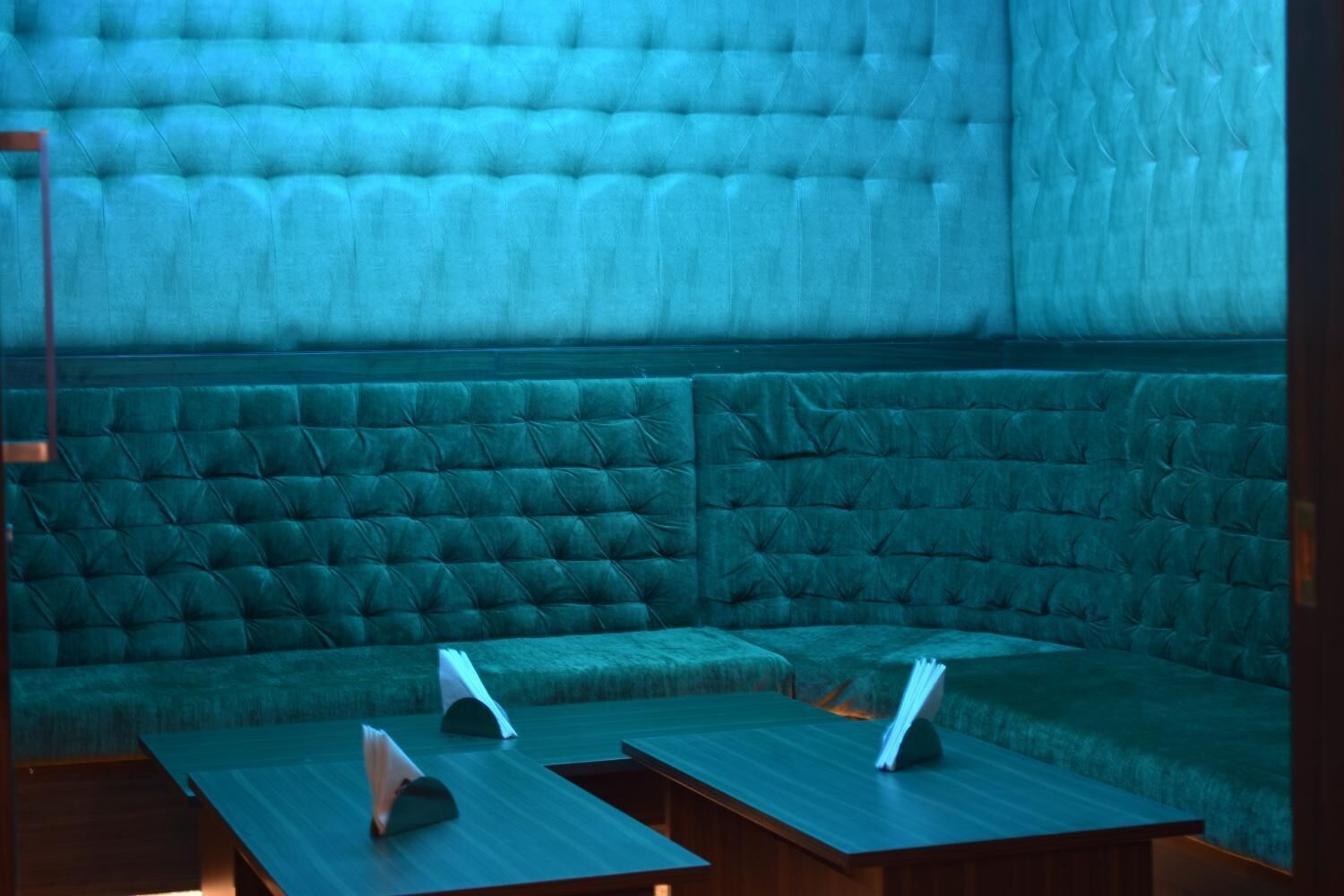 Una habitación con un sofá tapizado en verde y una mesa de madera con un menú.