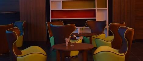 A seating area with colorful chairs and a small table, a bookshelf with various colors, and a sign indicating restricted admission.